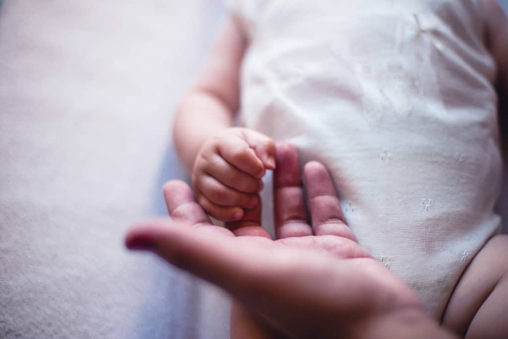 mother gently holding baby's hand